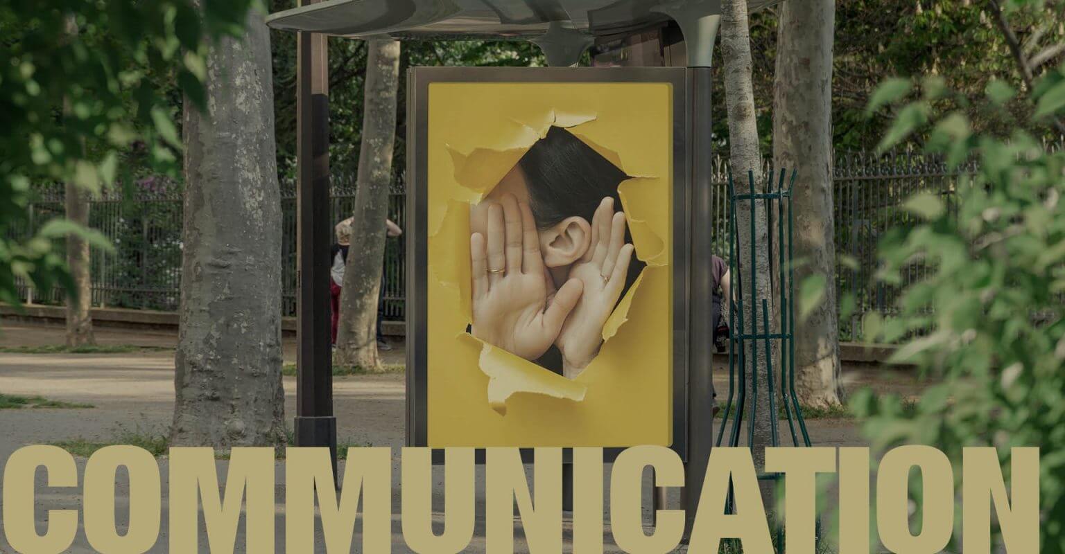 Abribus avec comme affiche publicitaire une femme qui tend l'oreille pour représenter la communication